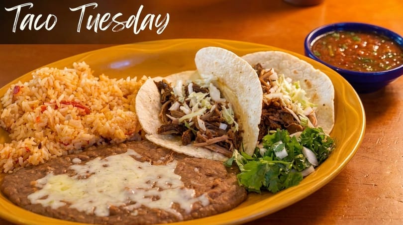 Two tacos with shredded meat and cabbage, rice, refried beans, and salsa on a yellow plate.